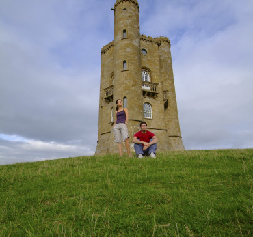 Couple taking in the view from the base of Broadway Tower, a folly built in 1797 at one of the highest points in the Cotwolds, Broadway Tower, Worcestershire, England.