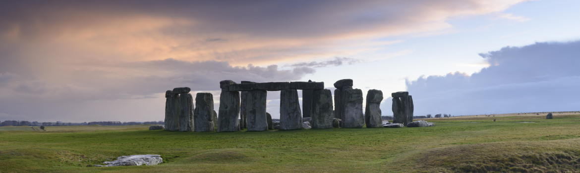 Stonehenge is a pre-historic henge and national landmark on the Wiltshire plain. It is a stone circle of standing stones, with some stones placed horizontally across the top of vertical stones. It is a UNESCO world heritage site. Gathering clouds over the site.