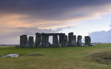 Stonehenge is a pre-historic henge and national landmark on the Wiltshire plain. It is a stone circle of standing stones, with some stones placed horizontally across the top of vertical stones. It is a UNESCO world heritage site. Gathering clouds over the site.