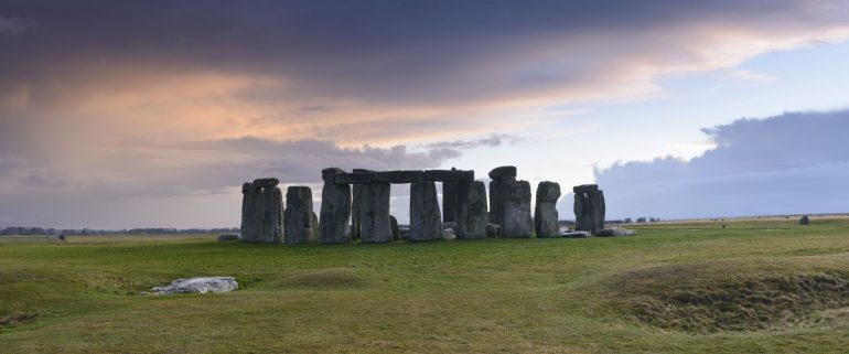 Stonehenge is a pre-historic henge and national landmark on the Wiltshire plain. It is a stone circle of standing stones, with some stones placed horizontally across the top of vertical stones. It is a UNESCO world heritage site. Gathering clouds over the site.