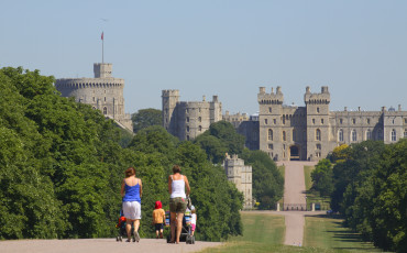 Two mothers with their young children, pushing prams along the Long Walk towards Windsor Castle in the distance. The Long Walk was commenced by Charles II from 1680-1685 by planting a double avenue of elm trees. The central carriage road was added by Queen Anne in 1710. It is a little less than three miles long. To the south of Windsor is The Great Park extending over some 14,000 acres of which 8,000 acres are forest. The public areas are predominantly woodland or open grassland.