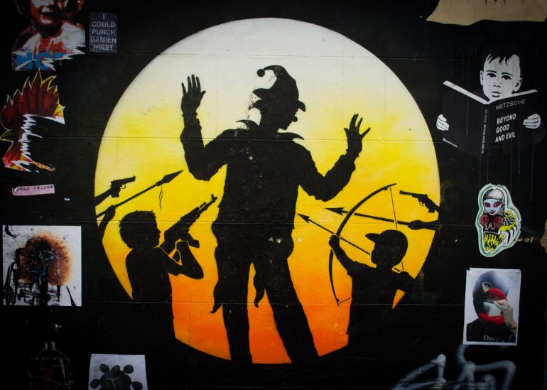 London Street Art: Otto Schade - Children pointing weapons at joker figure. Photo Credit: © Alex Lacey.