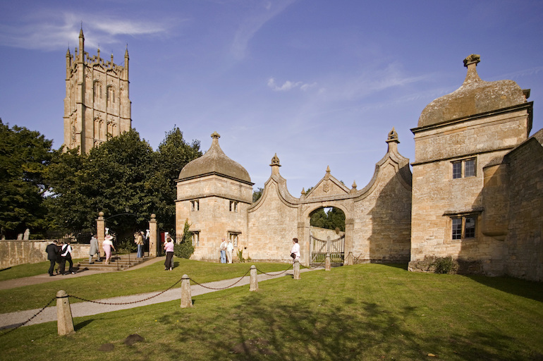 The Cotswolds: People in front of the Gatehouses of Old Campden House, with St James Church in the background. Photo Credit: © James Kerr via Visit England. 