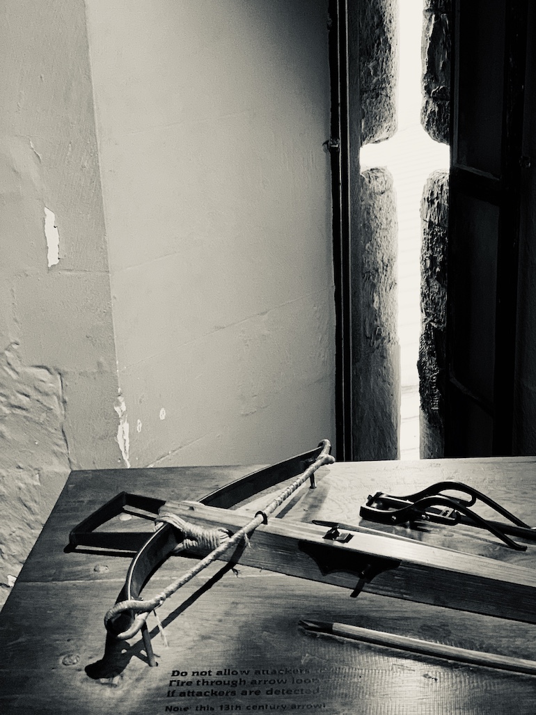 A crossbow rests by an arrow loop window in the Constable Tower at Tower of London. Photo Credit: © Antony Robbins. 