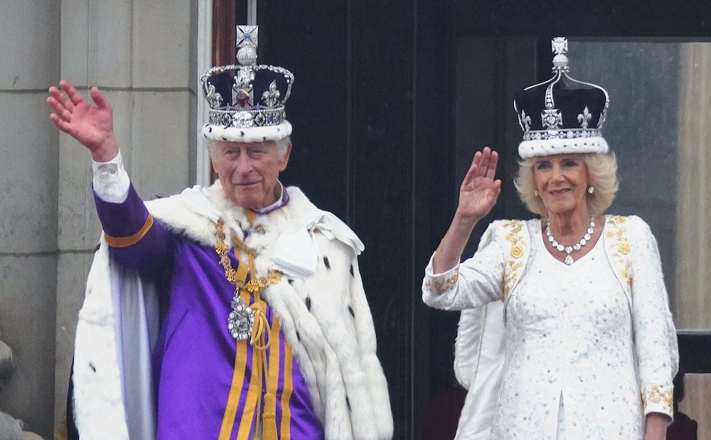 King Charles and Queen Camilla waving from the balcony of Buckingham Palace. Photo Credit: © Isaac Mayne/DCMS via Wikimedia Commons.